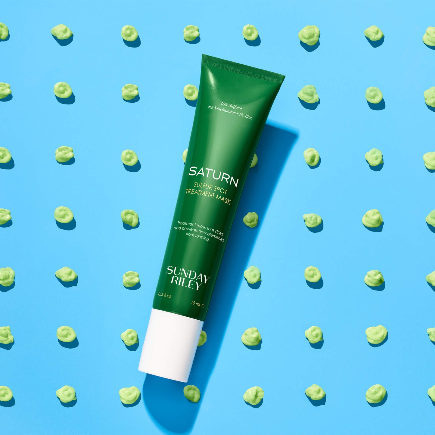Saturn tube lay over multiple green goop dots on a bright blue background 